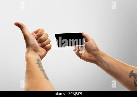 Spannende Momente. Nahaufnahme männliche Hände halten Telefon mit leerem Bildschirm während Online-Wiedergabe von beliebten Sportspielen, Meisterschaften. Copyspace für Werbung. Geräte, Gadgets, Technologien Konzept. Stockfoto