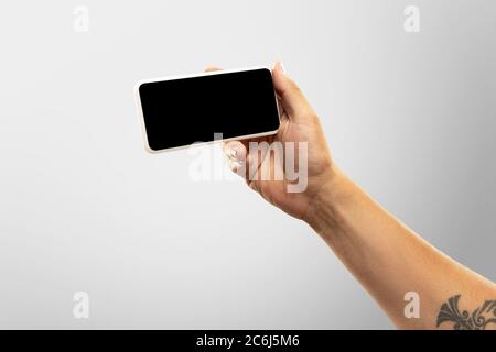 Spannende Momente. Nahaufnahme männliche Hände halten Telefon mit leerem Bildschirm während Online-Wiedergabe von beliebten Sportspielen, Meisterschaften. Copyspace für Werbung. Geräte, Gadgets, Technologien Konzept. Stockfoto