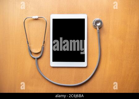 Tablet Touchpad Computer Gadget und Stethoskop auf dem Tisch in der Arztpraxis. Medizinisches Konzept. Blick von oben Stockfoto