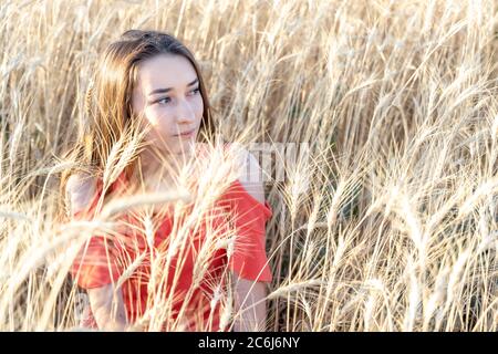 Schöne junge Frauen, die im Weizenfeld sitzen Stockfoto