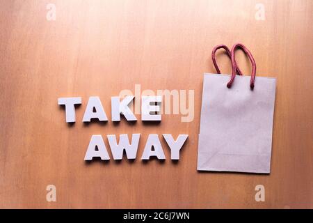 Take Away Service Konzept, Take Away Text und Papiertüte auf Holzhintergrund Stockfoto