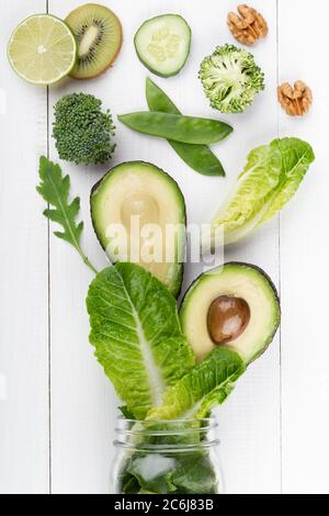 Glas Becher mit grünen Gesundheit Gemüse Salatblätter, Limette, Apfel, Kiwi, Avocado, Lebensmittelkonzept. Stockfoto