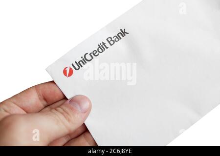 Tesanj, Bosnien und Herzegowina - 21. März 2020: Papierumschlag mit UniCredit-Bankschild in männlicher Hand isoliert auf weißem Hintergrund Stockfoto