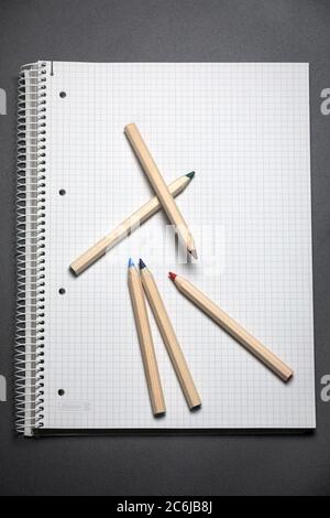 Flache Ansicht von weißem Notizbuch, Farbstifte auf einem Tisch. Vorbereitung auf eine Schule. Zurück zur Schule. Stockfoto