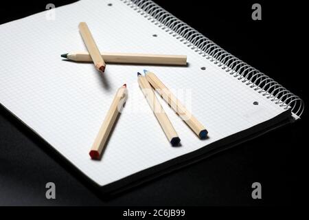 Flache Ansicht von weißem Notizbuch, Farbstifte auf einem Tisch. Vorbereitung auf eine Schule. Zurück zur Schule. Stockfoto