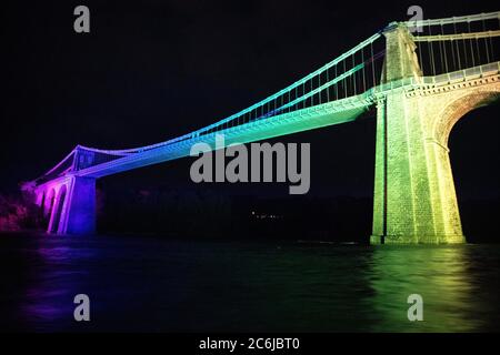 Bangor, Gwynedd, N Wales. Die Menai-Hängebrücke über die Menai-Straße wird in Regenbogenfarben beleuchtet, um 72 Jahre NHS zu feiern Stockfoto