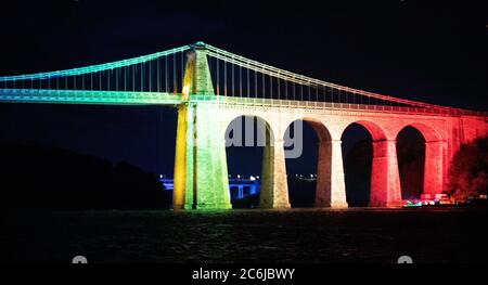 Bangor, Gwynedd, N Wales. Die Menai-Hängebrücke über die Menai-Straße wird in Regenbogenfarben beleuchtet, um 72 Jahre NHS zu feiern Stockfoto