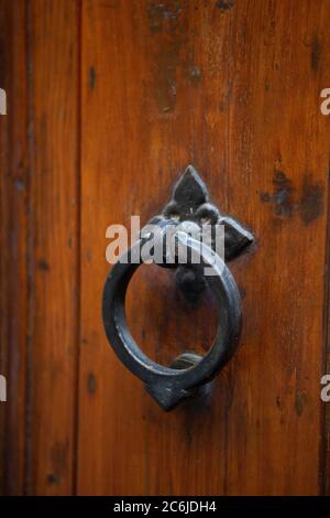 Antikes Metall Türknopf Kreis geformt auf braun Haustür. Vintage runder Griff an hölzerner Eingangstür. Nahaufnahme Stockfoto