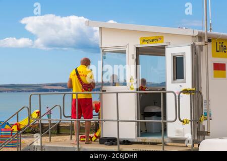 RNLI-Rettungsschwimmer patrouillieren an der Rettungsschwimmer-Kiosk-Hütte am Strand von Bournemouth, Dorset, Großbritannien, an einem schönen warmen, sonnigen Tag im Juli - Bournemouth Beach Stockfoto