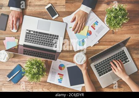 Mann und Frau arbeiten an ihren Computern. Die Aussicht von oben. Zwei Laptops, zwei Personen. Stockfoto