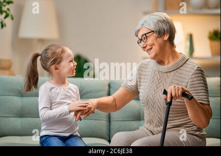 Ein nettes Mädchen und ihre Großmutter genießen die Zeit zusammen zu Hause verbringen. Familie spielt im Wohnzimmer. Stockfoto