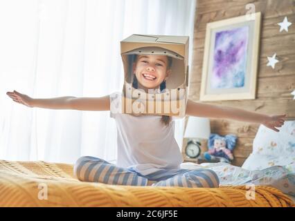 Kind Mädchen im Astronaut Kostüm mit Spielzeug Rakete spielen und träumen von einem Raumfahrer zu werden. Portrait von lustigen Kind im Schlafzimmer. Stockfoto