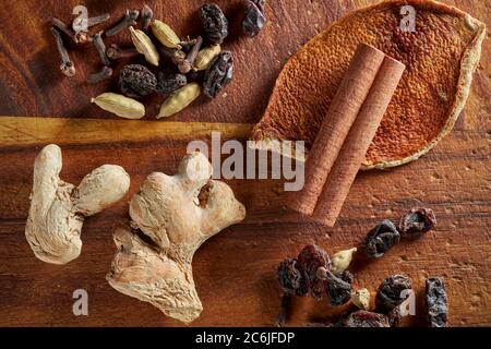 Eine Mischung aus trockenen Mulling Gewürze (Ingwer, Orangenschale, Rosinen, Nelken, Zimtstange, Kardamom-Schoten) auf Holzbrett. Stockfoto