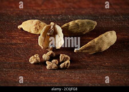 Nahaufnahme von getrockneten Kardamom-Schoten und Samen auf Holzbrett. Stockfoto