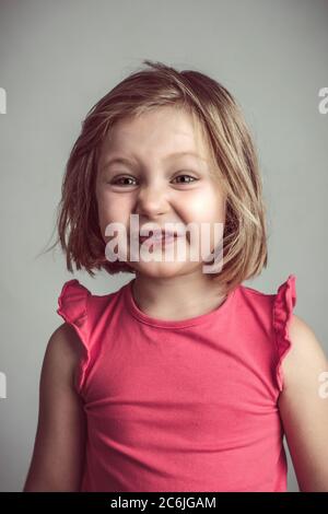 Blonde kaukasische kleine Mädchen machen eine hässliche und lustige Gesicht. studio-Porträt Stockfoto