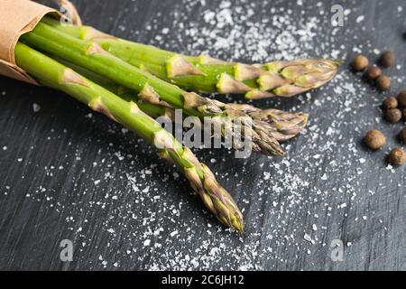 Nahaufnahme von Bio-frischem grünen Spargel mit Salz und Pfeffer. Konzept der gesunden vegetarischen Ernährung, Ernährung und Hausmannskost. Kopierbereich. Stockfoto