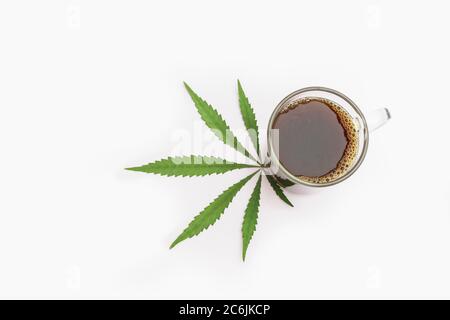 Tasse Cannabis-infundiertem Kaffee mit Marihuana-Blatt auf weißem Hintergrund. Draufsicht mit Platz für Text Stockfoto