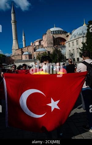 Istanbul, Türkei. Juli 2020. Die Menschen halten eine türkische Nationalflagge vor der Hagia Sophia und freuen sich über die gerichtliche Entscheidung über die Hagia Sophia. Der türkische Präsident Erdogan hat die Eröffnung des Gebäudes für das islamische Gebet angeordnet. Die Hagia Sophia (griechisch: Heilige Weisheit), erbaut im 6. Jahrhundert n. Chr., war die größte Kirche des Christentums und die Hauptkirche des Byzantinischen Reiches für fast ein Jahrtausend, wo Kaiser gekrönt wurden. Quelle: Yasin Akgul/dpa/Alamy Live News Stockfoto