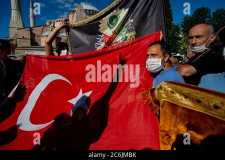 Istanbul, Türkei. Juli 2020. Die Menschen halten eine türkische Nationalflagge vor der Hagia Sophia und freuen sich über die gerichtliche Entscheidung über die Hagia Sophia. Der türkische Präsident Erdogan hat die Eröffnung des Gebäudes für das islamische Gebet angeordnet. Die Hagia Sophia (griechisch: Heilige Weisheit), erbaut im 6. Jahrhundert n. Chr., war die größte Kirche des Christentums und die Hauptkirche des Byzantinischen Reiches für fast ein Jahrtausend, wo Kaiser gekrönt wurden. Quelle: Yasin Akgul/dpa/Alamy Live News Stockfoto