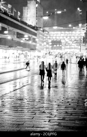 Silhouetten von Menschen, die im Regen in der Stadt Straße gehen. Stockfoto