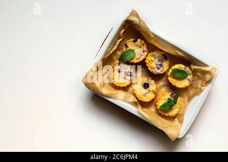 Hausgemachte Hüttenkäse Muffins mit Heidelbeeren in einem Gericht auf weißem Hintergrund. Flach legen, kopieren Raum Stockfoto