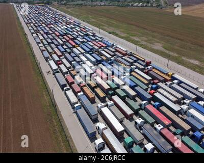 Frachttransport und Logistik warten viele LKWs im Hafenbereich auf ihre Abladung. Eine lange Reihe von Lastwagen mit Getreide. Stockfoto