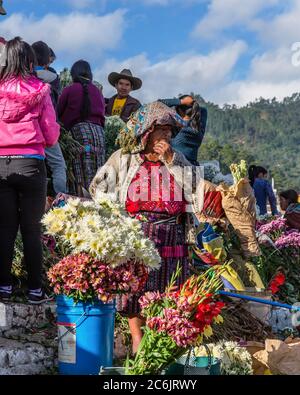 Guatemala, El Quiche Department, Chichicastenango, Quiche Maya Frau in traditioneller Kleidung Verkauf von Blumen auf den Stufen der Kirche von Santo Tomas. Stockfoto