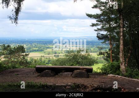 Blick auf Cheshire von der Stormy Point Gegend, inklusive einer Holzbank und Bäumen, am Alderley Edge in Cheshire, England Stockfoto