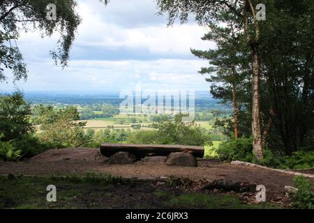 Blick auf Cheshire von der Stormy Point Gegend, inklusive einer Holzbank und Bäumen, am Alderley Edge in Cheshire, England Stockfoto