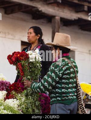 Guatemala, El Quiche Department, Chichicastenango, EIN Quiche Maya Mann kauft eine Bouqet von Blumen auf dem Blumenmarkt auf den Stufen der Kirche von Santo Tomas. Stockfoto