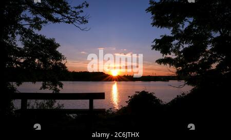 Atemberaubender Sonnenuntergang über dem Wasser. Strahlen der Sonne, die auf dem Wasser reflektiert werden. Ferienlandschaft am Meer. Ruhige entspannende Szene mit einem schönen bunten Stockfoto
