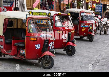 Guatemala, Solola Department, San Pedro la Laguna, EINE Reihe von Mototaxis warten auf Passagiere am Bootsanleger. Mototaxis oder Tuk Tuks aus Indien sind eine sehr wirtschaftliche Form des öffentlichen Verkehrs in vielen von Mexiko und Mittelamerika. Stockfoto