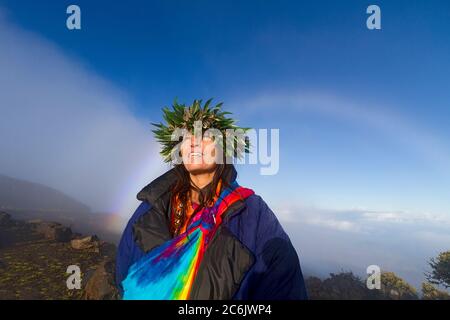 Barbara Bohonu, spirituell/kulturelle Heiler genießen einen Regenbogen kurz nach Sonnenaufgang am Haleakala Krater, Maui, Hawaii, USA. Stockfoto