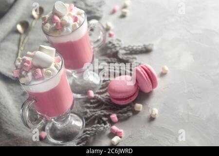 Heiße Schokolade in Rosa mit Schlagsahne und Marshmallow-Süßigkeiten in 2 Glaskrügen, süße Pastell-makronen. Platz für Text kopieren. Horizontal. Stockfoto