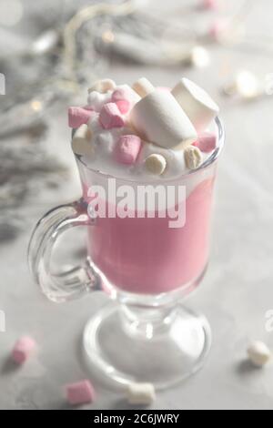 Heiße Schokolade in Rosa mit Schlagsahne und Marshmallow-Süßigkeiten in einem Glaskrüge auf grauem Hintergrund Stockfoto