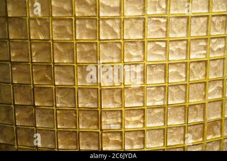 Gelber Block mit Glaskarierung. Goldenes Glas oder Mosaik smalt mit gelber Füllung der Nähte. Abstrakte geometrische Textur oder Hintergrund Stockfoto