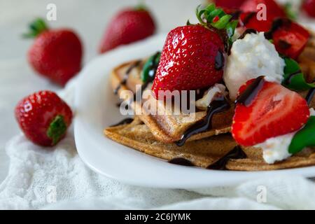 Belgische Waffeln mit Erdbeeren, Ricotta-Käse und Schokolade auf weißem Teller. Selektiver Fokus. Nahaufnahme Stockfoto