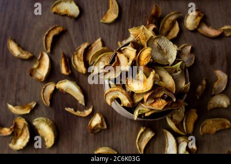 Hausgemachte sonnengetrocknete Bio-Apfelscheiben, knusprige Apfelchips, auf einem alten rustikalen Holztisch, flach liegend Stockfoto