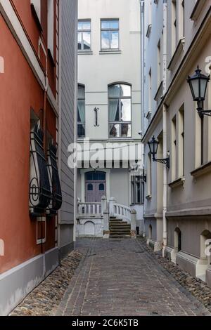 Enge Straße in der Altstadt von Riga mit Steinveranda und gepflasterter Straße. Stockfoto