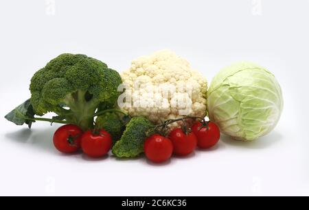 Kopf von Kohl, Blütenstände von Brokkoli und Blumenkohl und rot reifen Tomaten auf einem hellen Hintergrund. Naturprodukt. Natürlicher Farbton. Nahaufnahme. Stockfoto