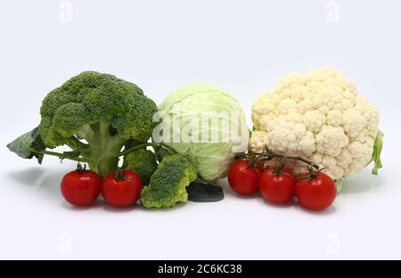 Kopf von Kohl, Blütenstände von Brokkoli und Blumenkohl und rot reifen Tomaten auf einem hellen Hintergrund. Naturprodukt. Natürlicher Farbton. Nahaufnahme. Stockfoto