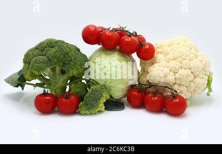 Kopf von Kohl, Blütenstände von Brokkoli und Blumenkohl und rot reifen Tomaten auf einem hellen Hintergrund. Naturprodukt. Natürlicher Farbton. Nahaufnahme. Stockfoto