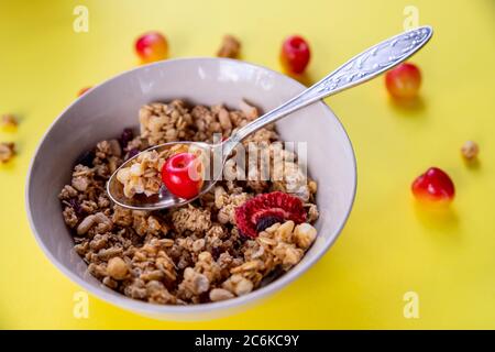 Leckeres und gesundes Vollkornmüsli-Frühstück, mit vielen trockenen Früchten, Nüssen, Körnern und einem frischen Kirschen.Haferflocken und frischen Beeren.Essen gemacht Stockfoto