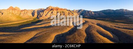 Am frühen Morgen erhellt Sonnenlicht eine wunderschöne Berglandschaft, die aus der Wüste im Red Rock Canyon unweit von Las Vegas, Nevada, aufsteigt. Stockfoto