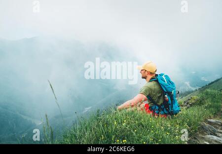 Backpacker Mann hat eine Pause genießen bewölkt Talboden Wandern durch die nebligen bewölkten Wetter Bergkette. Aktiv Sport Backpacking gesund l Stockfoto