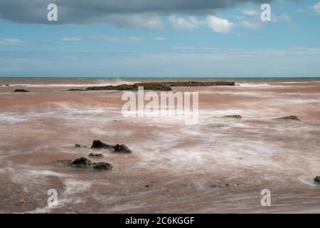 Lange Exposition der Gezeiten über Felsen auf Budeigh Salterton in Devon Stockfoto