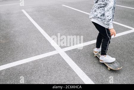 Teenager Skateboarder Junge mit einem Skateboard auf Asphalt Spielplatz macht Tricks. Jugend Generation Freizeit Ausgaben Konzept Bild. Stockfoto