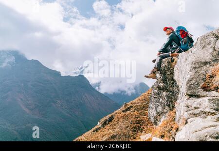 Junge Wandererin Backpacker weiblich sitzt am Klippenrand und genießt das Imja Khola Tal während der Höhenwanderung des Everest Base Camp (EBC) Route nea Stockfoto