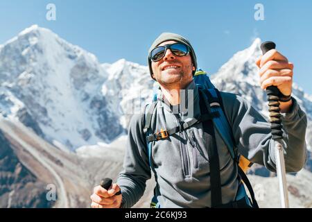 Portrait des lächelnden Wanderers auf Taboche 6495m und Cholatse 6440m Gipfel Hintergrund mit Trekkingstöcken, UV-schützende Sonnenbrille. Er genießt den Berg Stockfoto