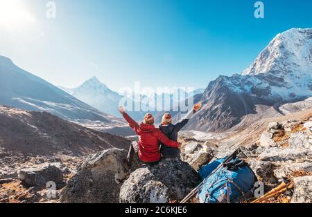 Paar aufsteigende Arme jubeln Everest Base Camp Trekkingroute nahe Dughla 4620m. Backpacker links Rucksäcke und Trekking Stöcke und genießen Tal vie Stockfoto